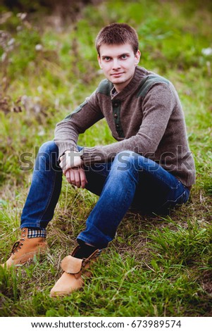 Young handsome man sitting on the nature by the lake