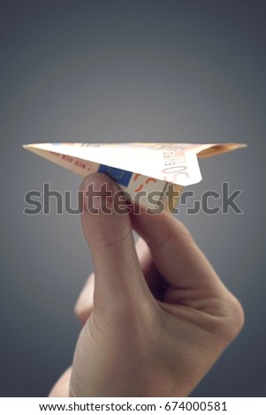 Person holding paper airplane made of 50 euro note, close-up of hand