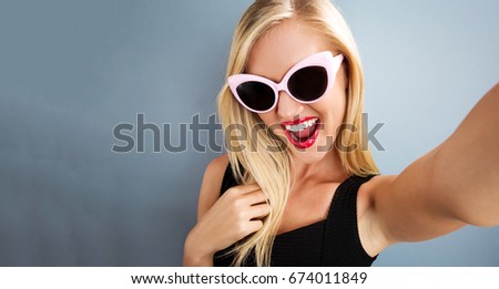 Young woman taking a selfie on a gray background