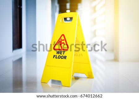 Sign showing warning of wet floor on wet floor in sunrise 