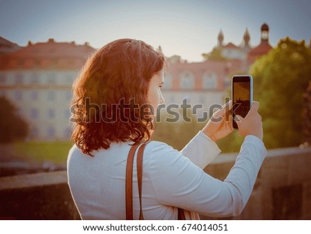 Soft focus portrait of female person holding smartphone in hand taking picture of sunrise view