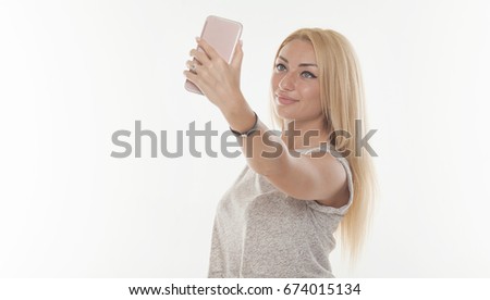 Young beautiful lady taking a selfie self portrait of herself smiling at he camera. Close up portrait of a attractive woman holding a smartphone digital camera.