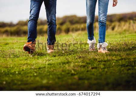 Beautiful couple in love in jeans and boots  walking around the field Royalty-Free Stock Photo #674017294