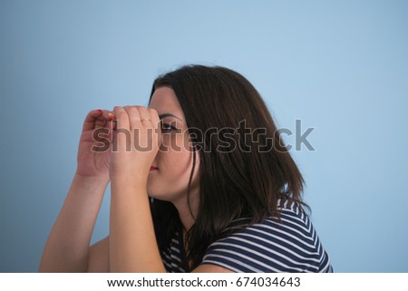 Woman looking through hands, making binoculars