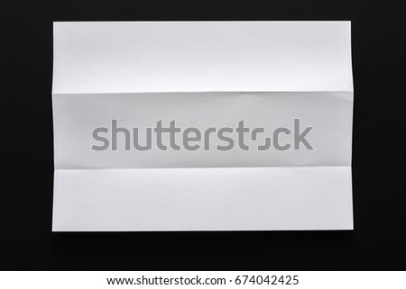 White folded sheet of paper on black background. Abstract backdrop, art, origami concept, copy space