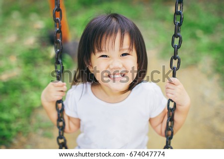 Close up picture of happy face kid who playing swing.Free play in the playground for baby and toddler is important activity for child development.