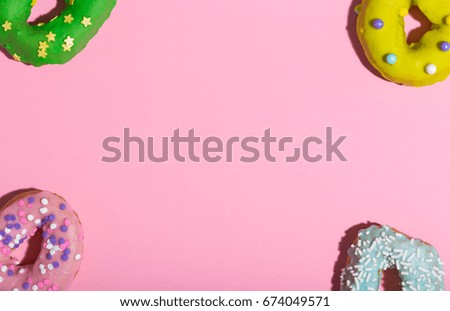 Colorful glazed donuts on a pink background