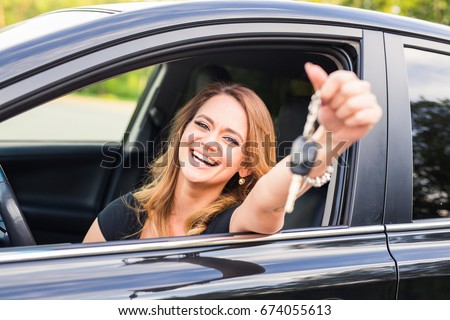 Young woman getting her key in the car. Concept of rent car or buying car Royalty-Free Stock Photo #674055613