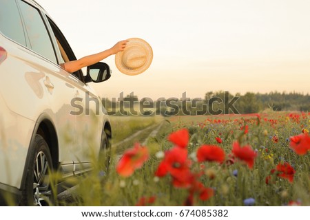 Summertime, summer fun, enjoying, relaxing, tourism, travel, leisure time, vacation mode, happiness concept. Woman enjoying summer vacation. Hands holding hat out of  car window.  Selective focus. Royalty-Free Stock Photo #674085382