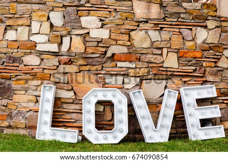 A word of love near the stone wall. Photo area in wedding decoration in the park