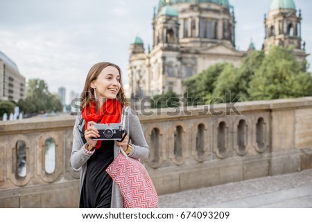 Young woman tourist with photo camera enjoying traveling in Berlin city walking on the old bridge near the famous cathedral