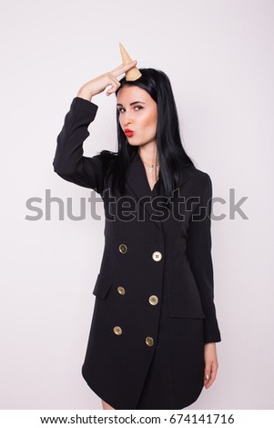 young slim brunette girl in stylish black Cape. posing in a photo Studio. white background. clear skin and healthy hair. emotional portrait.waffle cone for ice cream