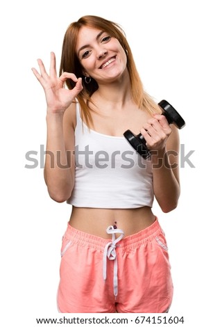 Beautiful sport woman with dumbbells making OK sign