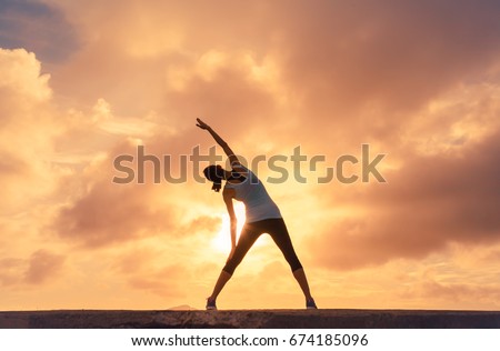 Woman doing stretching warm up exercise outdoors against a beautiful sunset.  Royalty-Free Stock Photo #674185096