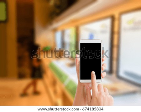 woman use mobile phone and blurred image of the girl looking at the big monitor