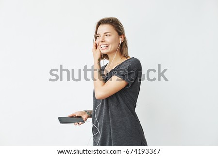 Cheerful young pretty girl smiling listening music in headphones dancing over white background.