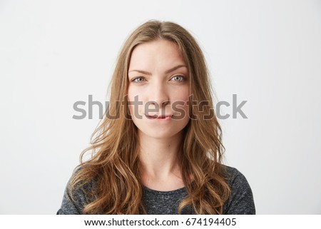 Young beautiful girl suspiciously looking at camera thinking over white background.
