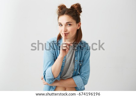 Portrait of young Beautiful cute girl with two buns smiling looking at camera showing to keep silence over white background.