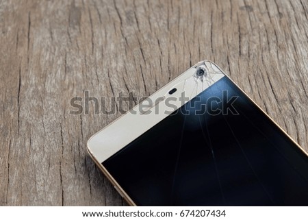 Phone screen broken on wooden floor, select focus