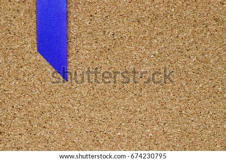 Blue ribbon placed on cork board background with the space for add text