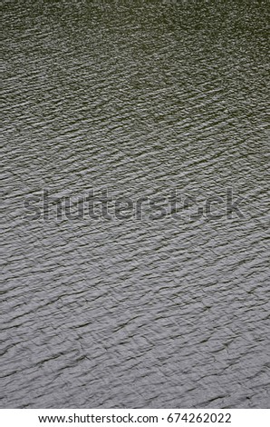 The texture of dark river water under the influence of wind, imprinted in perspective. Vertical image