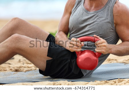 Fitness man lifting kettlebell weight training russian twist exercise. Exercising on beach training with kettlebells working out core, obliques and abdominal abs muscles working out six pack. Royalty-Free Stock Photo #674314771