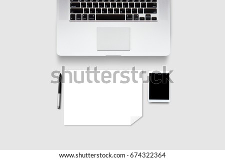 Top view of laptop and tablet mobile phone with English keyboard and pen and blank white paper on white background