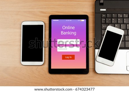 Digital tablet with Online Banking on screen with smartphone and laptop on wooden desk for Online Banking Payment Finance Concept, top view