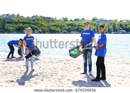 Group of young people cleaning beach area. Volunteer concept