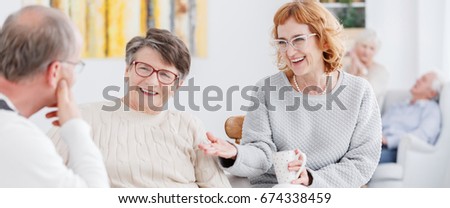 Two happy senior women talking to a man with glasses