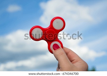 Red spinner in female hand on background of sky