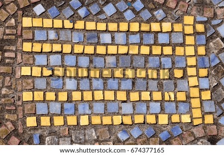 Pattern of coloured mosaic tiles with horizontal rows of parallel yellow tiles on a pastel background