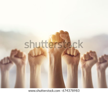 People raised fist air fighting for their rights with sunlight effect,  labor movement, election movement, copy space Royalty-Free Stock Photo #674378983