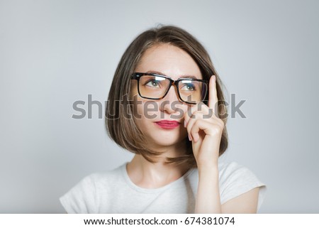 Beautiful girl have a good idea, wears glasses, isolated on gray background