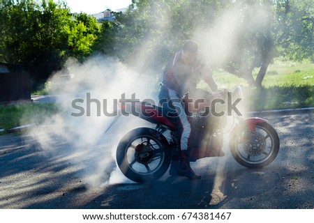 Biker on a motorcycle drifts in smoke. Biker burns the tire on a motorcycle