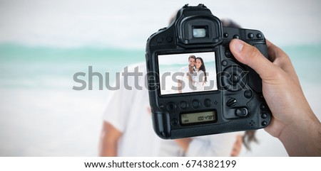 Composite image of cropped hand of photographer holding camera 