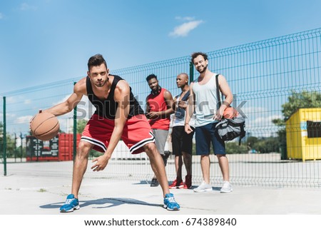 group of young multicultural men playing basketball on court