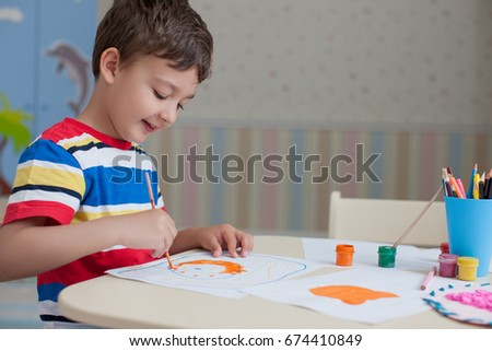 Child boy draws with colored pencils in kindergarten or in his room                     