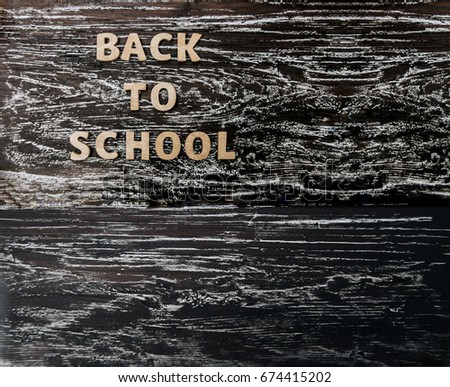 words -  Back to School made from wood letters lie on wooden table or chalkboard  background. Education, back to school idea, sign, symbol, concept of 1th September