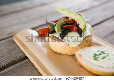 Close up of vegetables with cheese and bun on cutting board