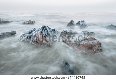 landscape with dreamy stones in the surf at slow shutter speed 