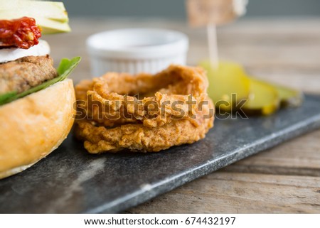 Onion rings by burger on slate at table