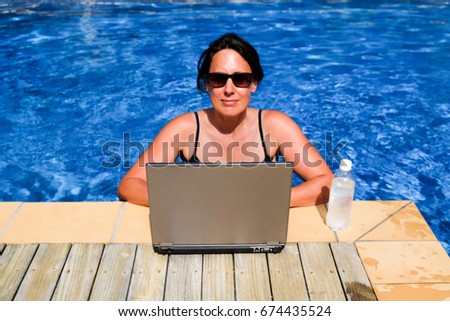 Female executive workaholic working on laptop computer in swimming pool on vacation - work from anywhere concept