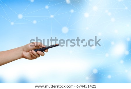 close up man hand holding remote  controller over network neutral connectivity blue color background ,advance technology concept