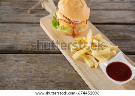 French fries with burger and sauce on cutting board