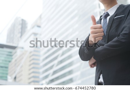 close up businessman showing hand thumb up over building background,advance business , we are hiring concept