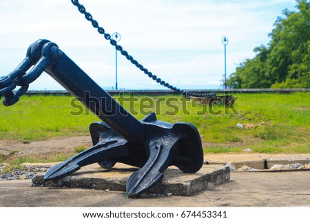 old black anchor and iron chain with green background grass yard and sky