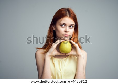 Woman with an apple on a gray background                               