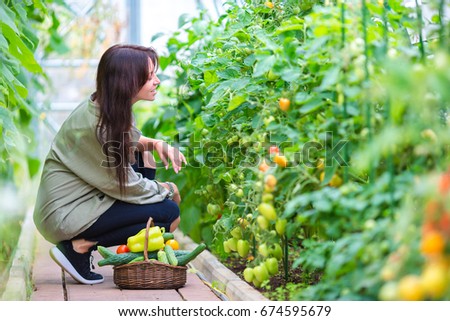 young woman holding a basket of greenery and onion in greenhouse
