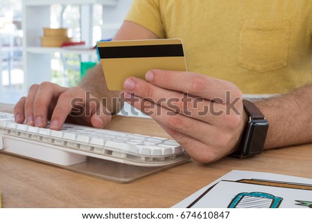 Male executive doing online shopping on computer at desk in the office